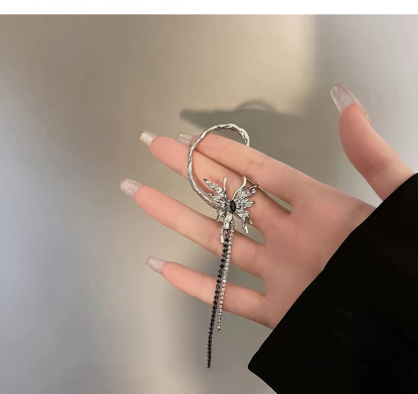 Liquid metal butterfly tassel ear cuff held in hand.