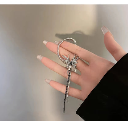 Liquid metal butterfly tassel ear cuff held in hand.