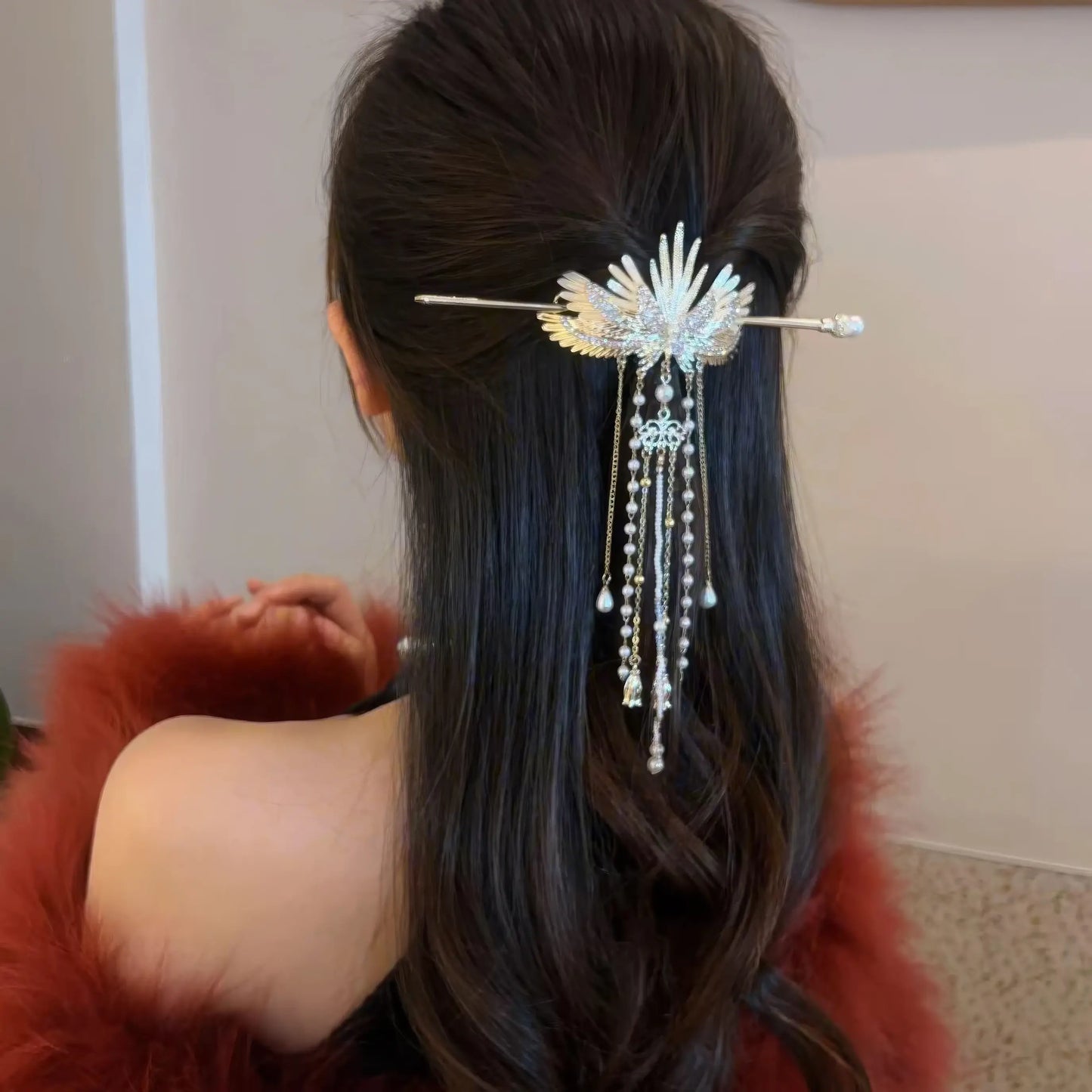Back view of long wavy hair half-fixed by angel wing hairpin, red fur outfit highlighting the hair accessory's elegant sparkling details.