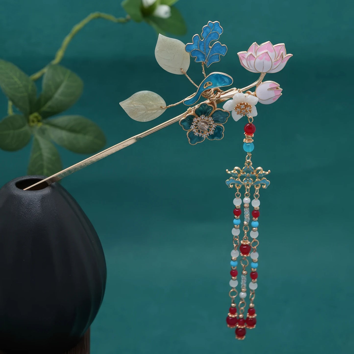 Hairpin inserted into a black vase, with the full tassel hanging down against a teal background, showing the complete length of the beaded drops.