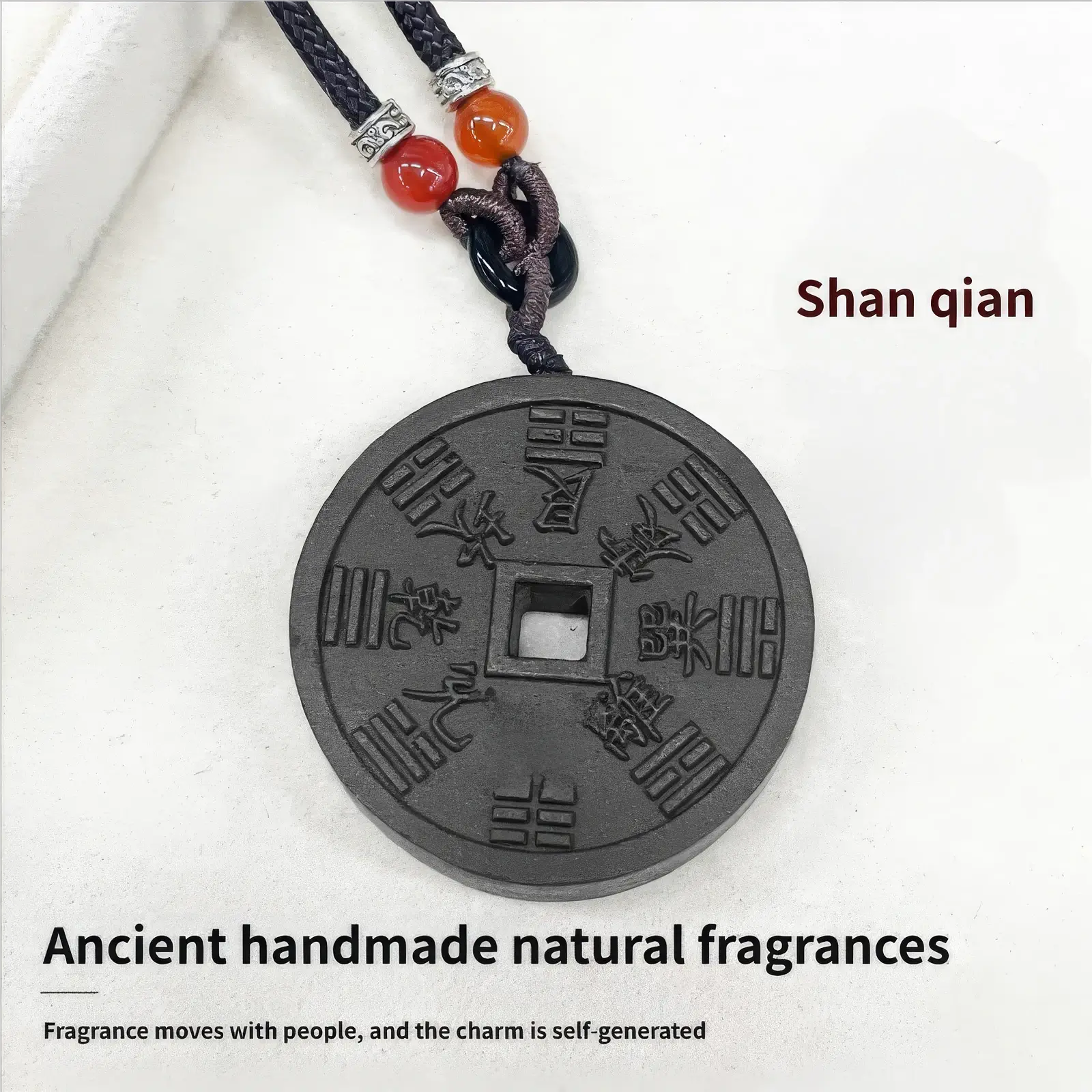 Full display of the Mountain Ghost Amulet incense pendant against a white background, with the name "Shan qian" on the top right, and English text below reading "Ancient handmade natural fragrances. Fragrance moves with people, and the charm is self - generated".
