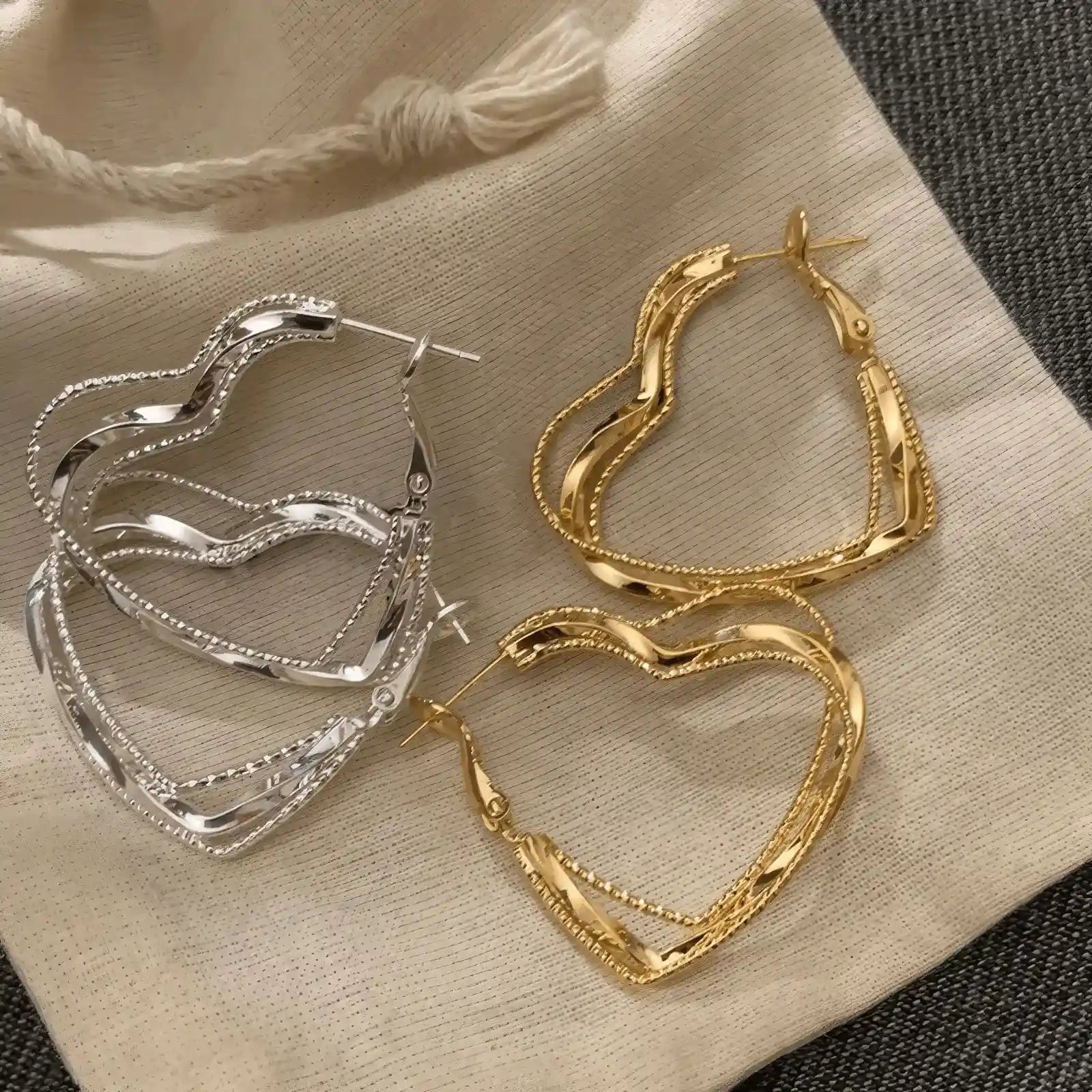 Mixed gold and silver multi - layered heart earrings, displayed on fabric, emphasizing the variety of metallic tones
