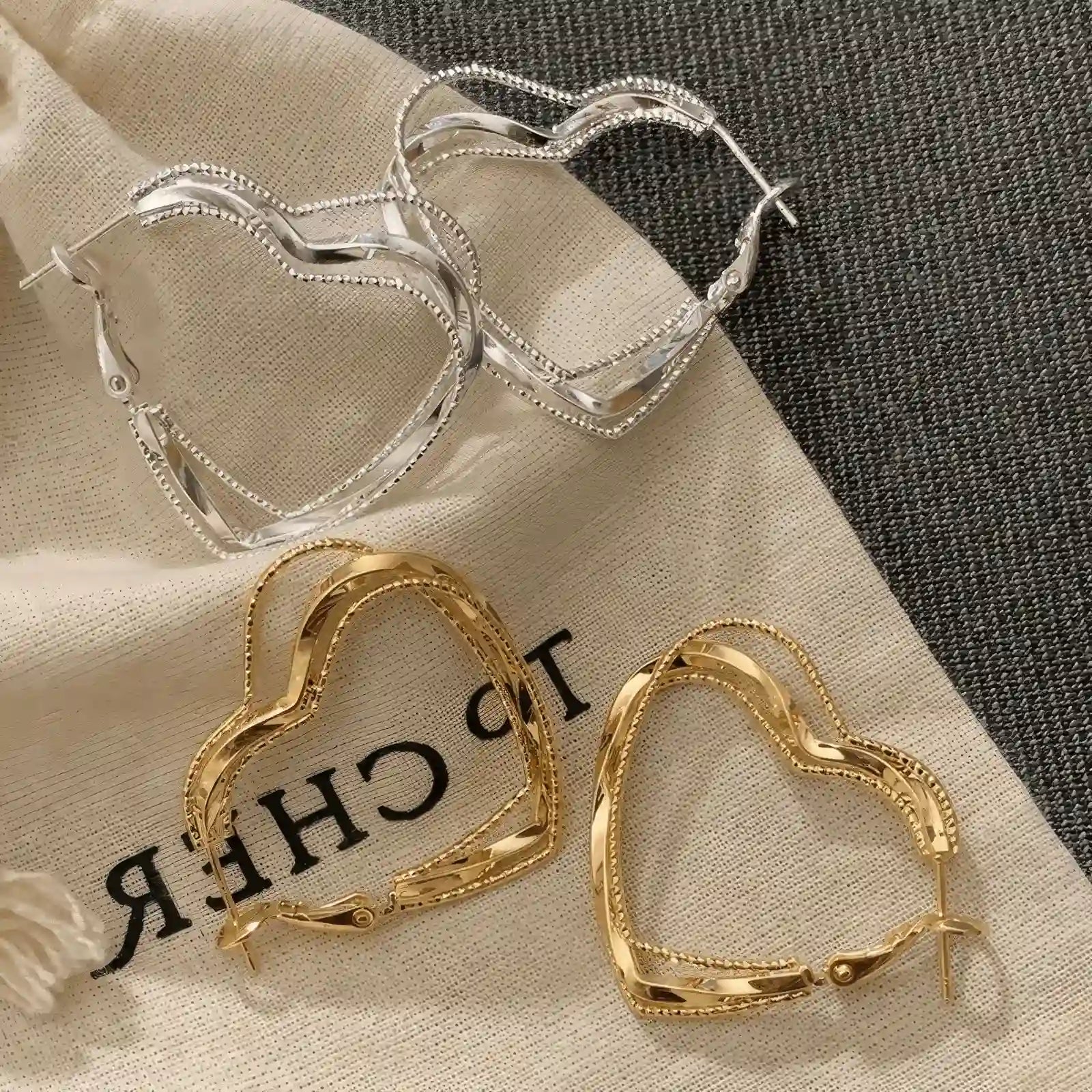 Mixed gold and silver multi - layered heart earrings, displayed on fabric, showcasing the contrast of metallic tones