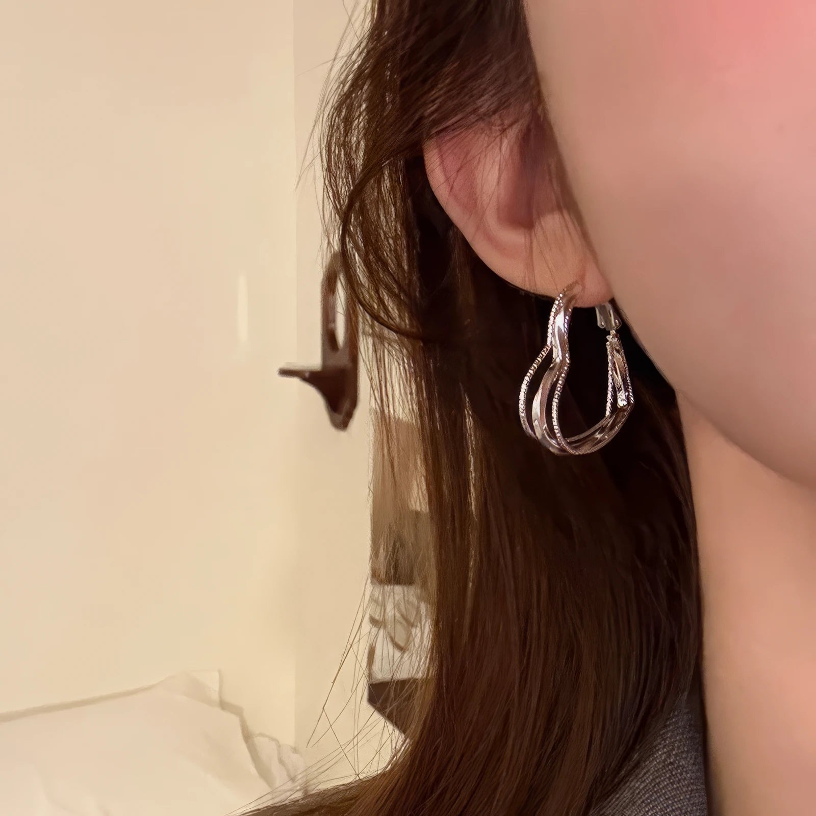 Silver multi - layered heart earring worn, showcasing the elegant, layered heart look on the ear