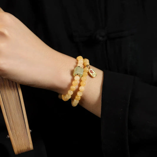 Natural cream - yellow jade bead bracelets worn on wrist, stacked together.