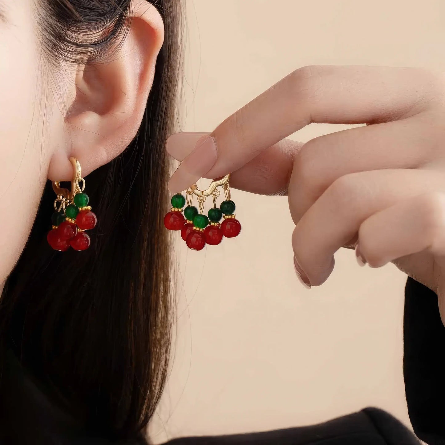Neo - Chinese palace - style beaded earring worn, with hand holding the other earring, showcasing the vibrant red and green bead design.