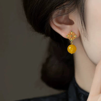 Neo - Chinese style yellow bead earring worn, emphasizing the elegant look of the golden filigree top and yellow bead.