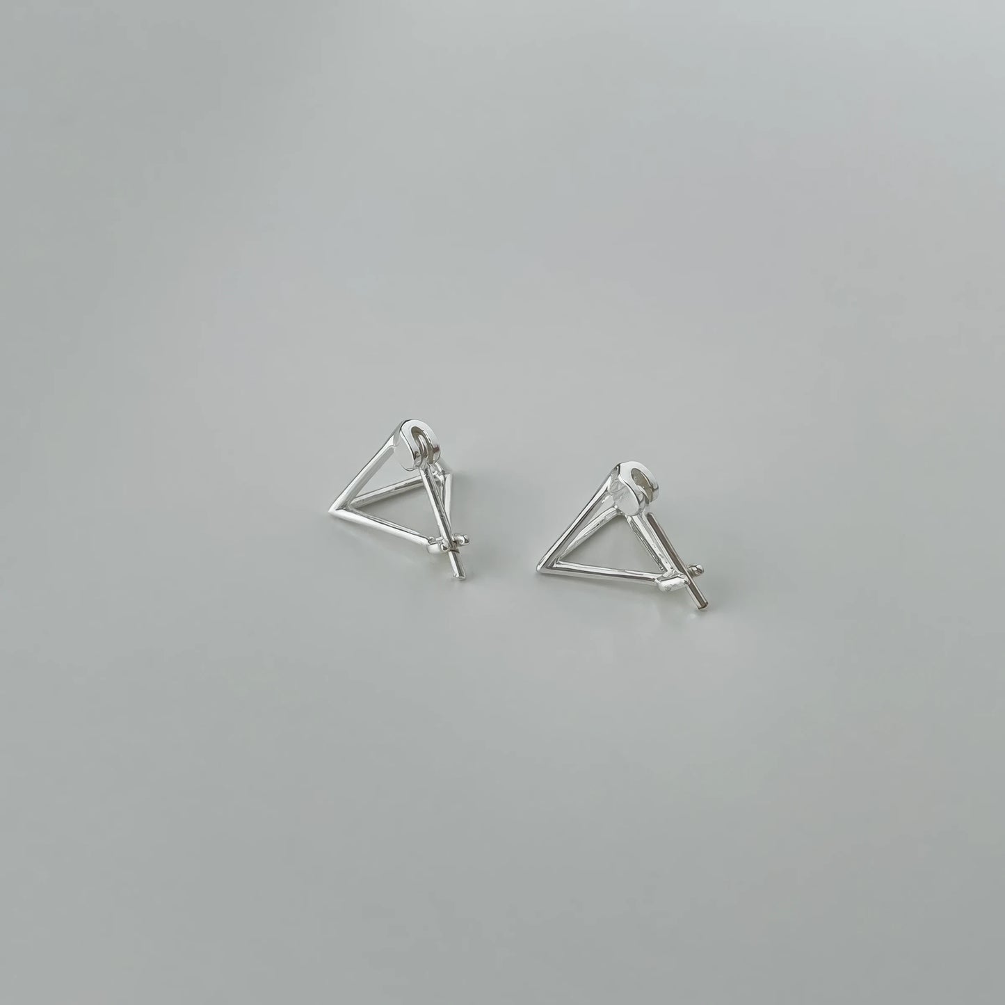 Pair of new geometric hollow triangle - shaped earrings, isolated on gray background, highlighting the intricate open - work design.