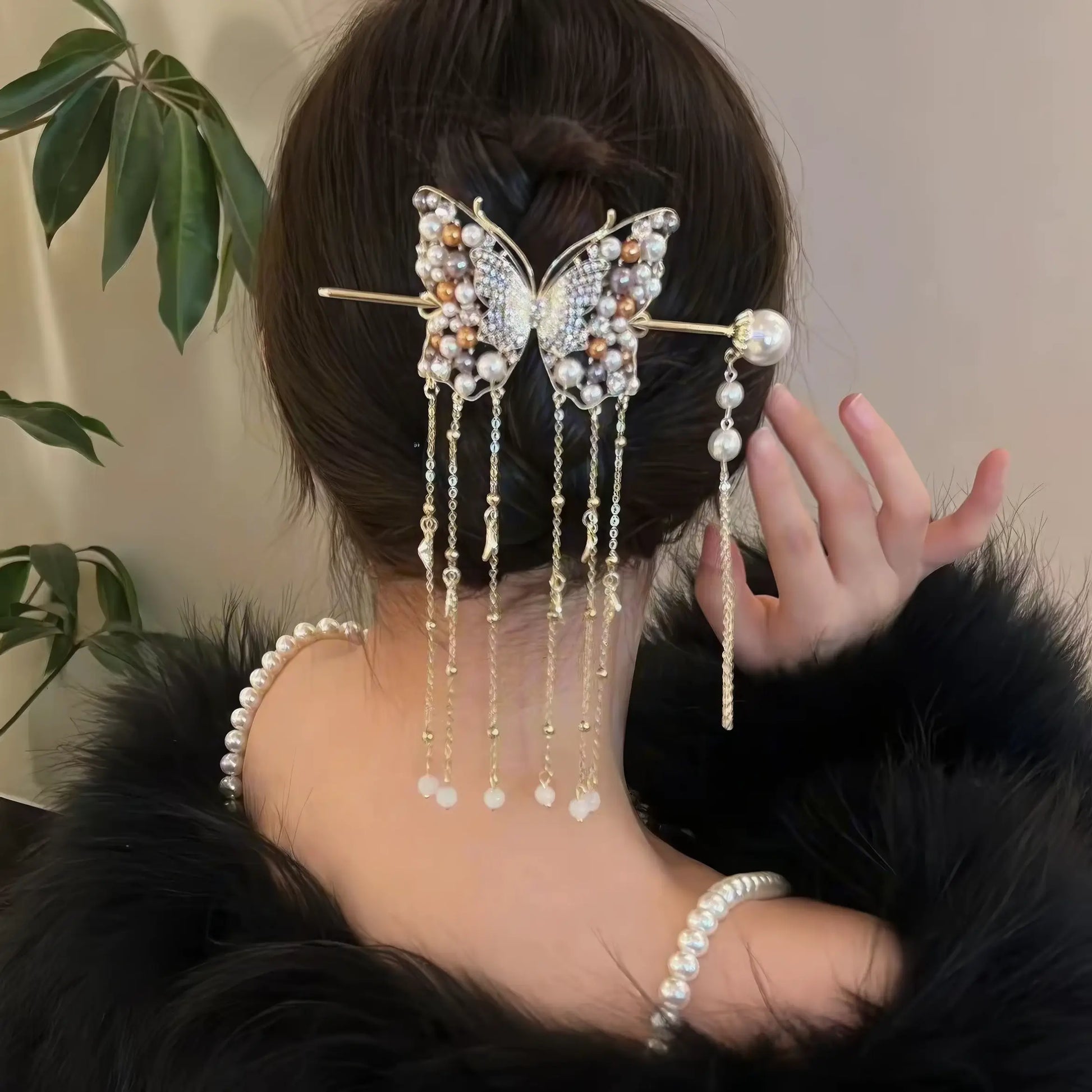 Close-up back shot of half-up hairstyle with golden butterfly pearl tassel hairpins, hand beside hair to display the dangling tassel layers clearly.