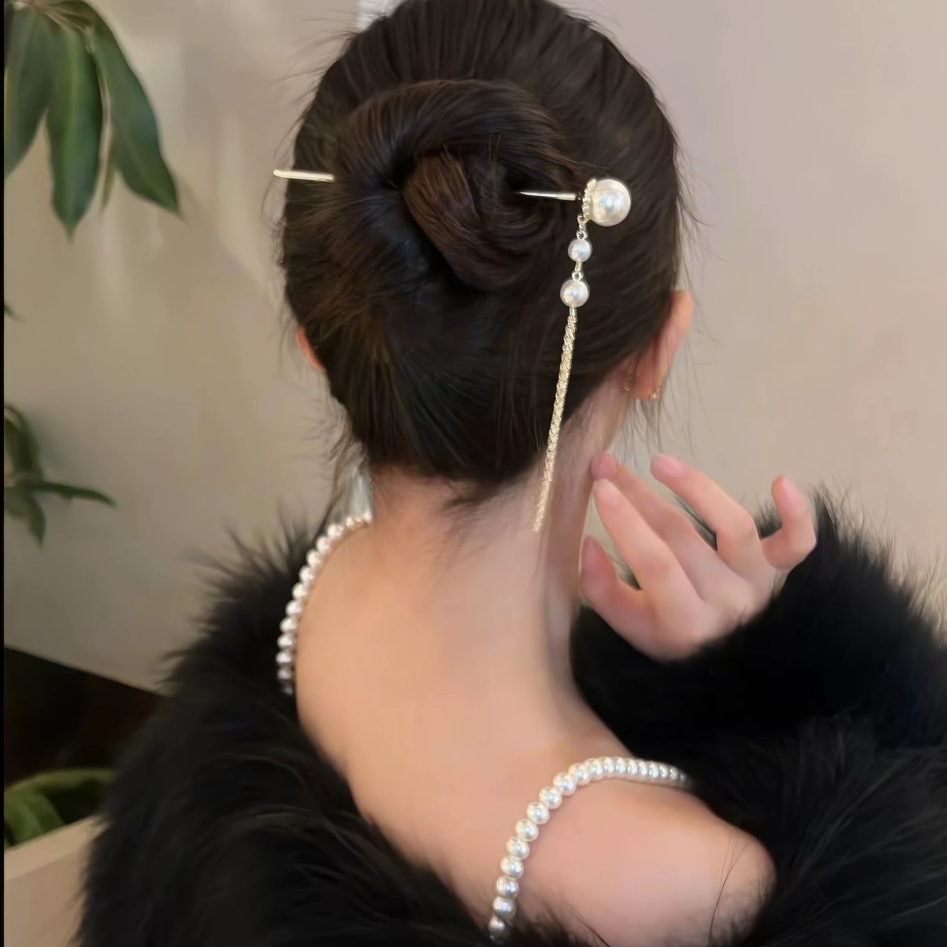Golden butterfly pearl tassel hairpin set fixed neatly into a low bun updo, showing how the two matching hair sticks decorate compact vintage hairstyle.