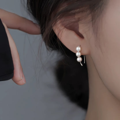 Pearl hoop earrings worn, paired with a dark top, showcasing the minimalist yet stylish clustered pearl look
