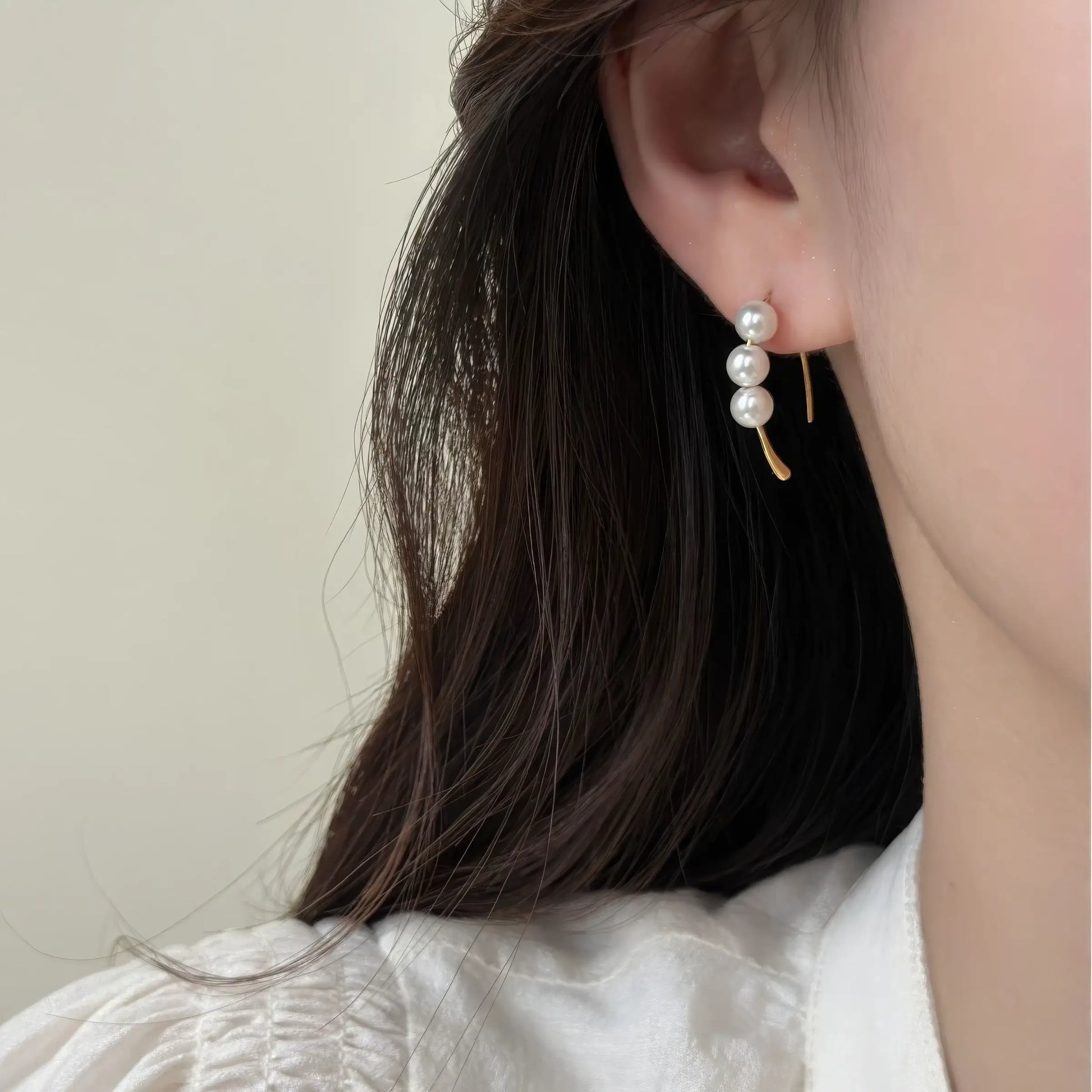 Pearl hoop earrings with small gold detail worn, showcasing the clustered pearl design on the ear