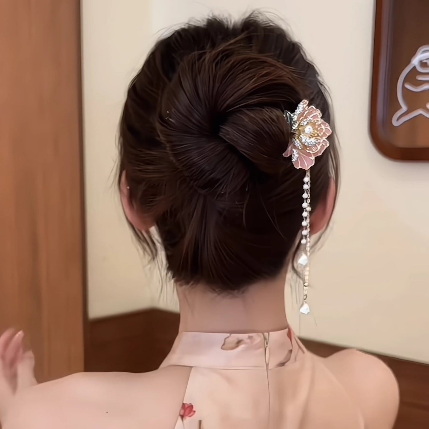 Back view of a peony flower hairpin worn in a neat bun, featuring a pink peony design with a single pearl chain tassel, paired with a light pink cheongsam.