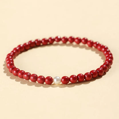 Purple gold cinnabar bead bracelet featuring a single pearl, isolated on a light - colored background.