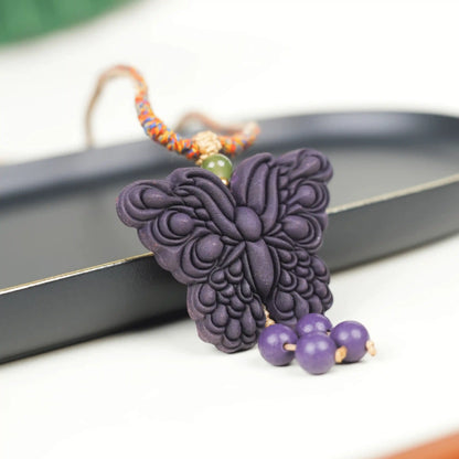 Close-up of the "Purple Qi Coming from the East - Double-Sided Butterfly Incense Pendant" placed on a black tray, with a vivid and lifelike butterfly shape and hanging beads adding a sense of agility.