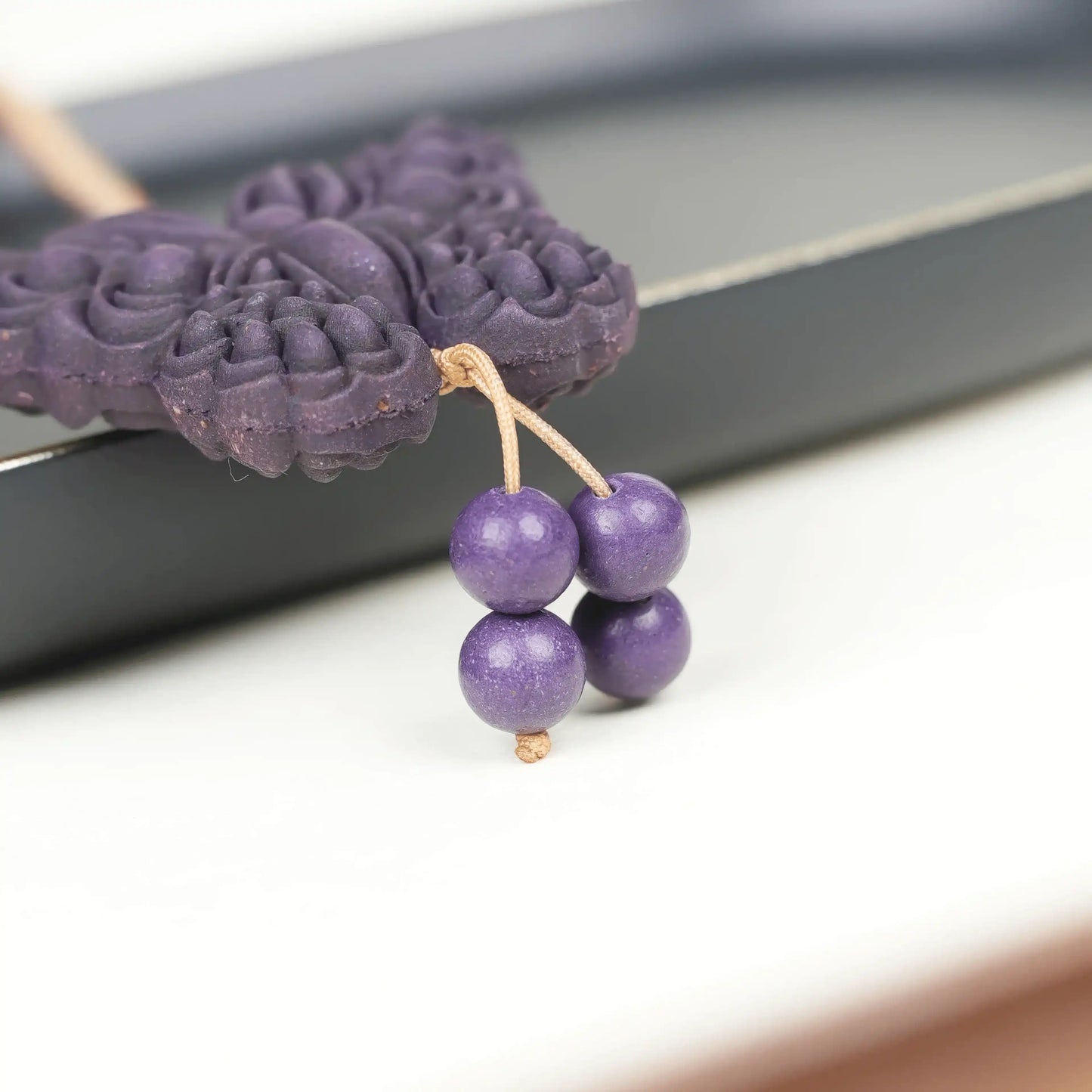 Partial detail view of the "Purple Qi Coming from the East - Double-Sided Butterfly Incense Pendant," featuring a dark purple butterfly shape with several round purple beads hanging below, and the carved texture on the pendant’s surface clearly visible.