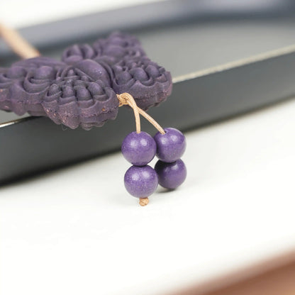 Partial detail view of the "Purple Qi Coming from the East - Double-Sided Butterfly Incense Pendant," featuring a dark purple butterfly shape with several round purple beads hanging below, and the carved texture on the pendant’s surface clearly visible.