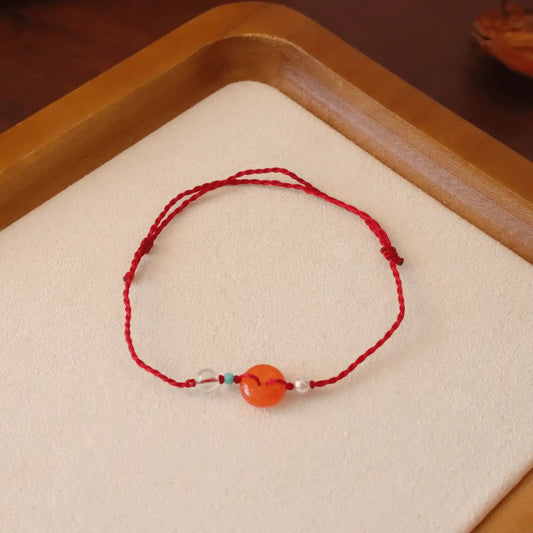 Red string bracelet with Nan Hong gourd peace buckle isolated on a light - colored surface.