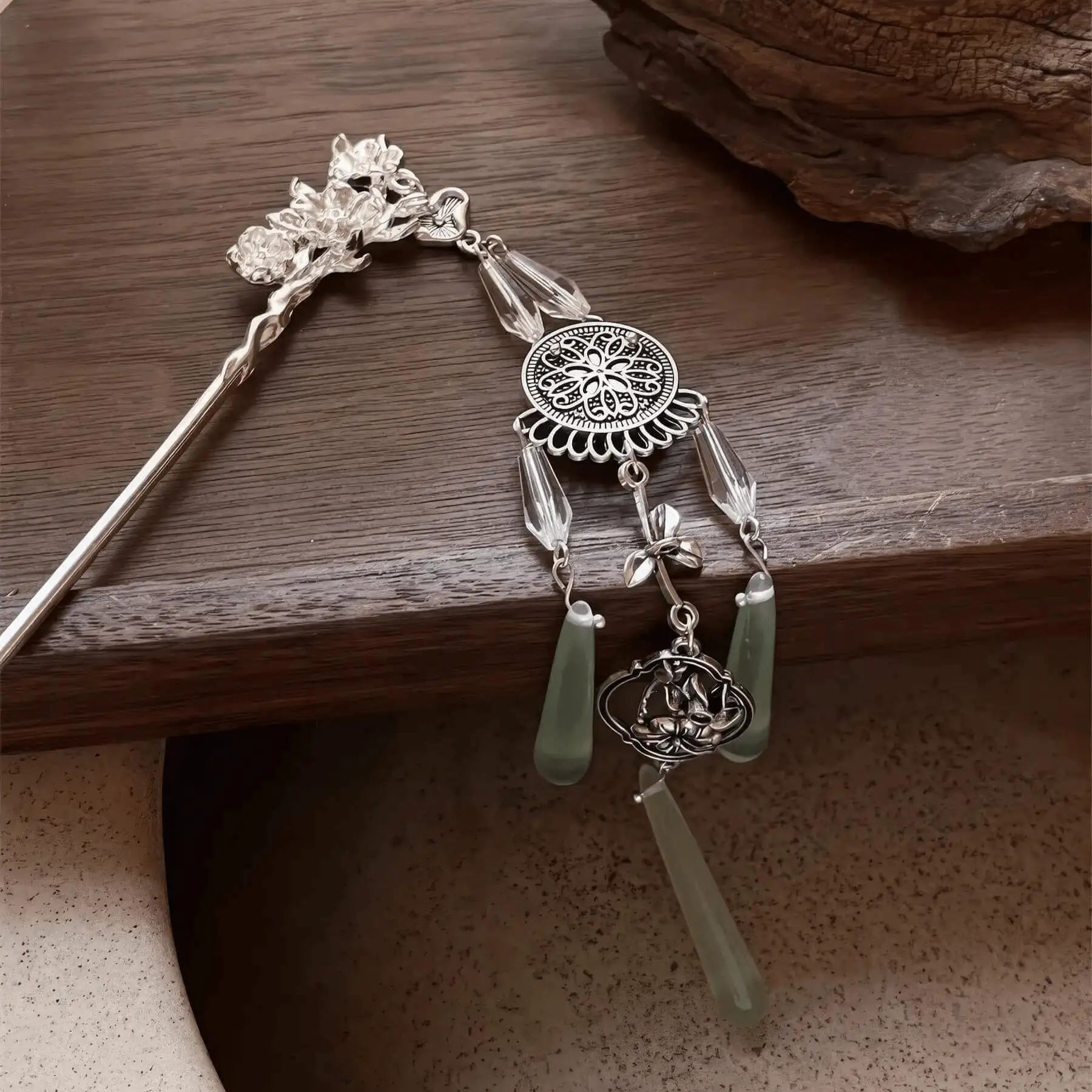 An angled view of the retro silver wind chime hairpin displayed on a dark wooden surface, emphasizing the three-dimensional structure of the tassels and metalwork.