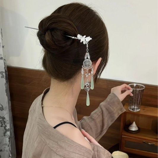 A retro silver wind chime water drop tassel hairpin worn in a casual low bun, shown from the back view, paired with a light brown top.