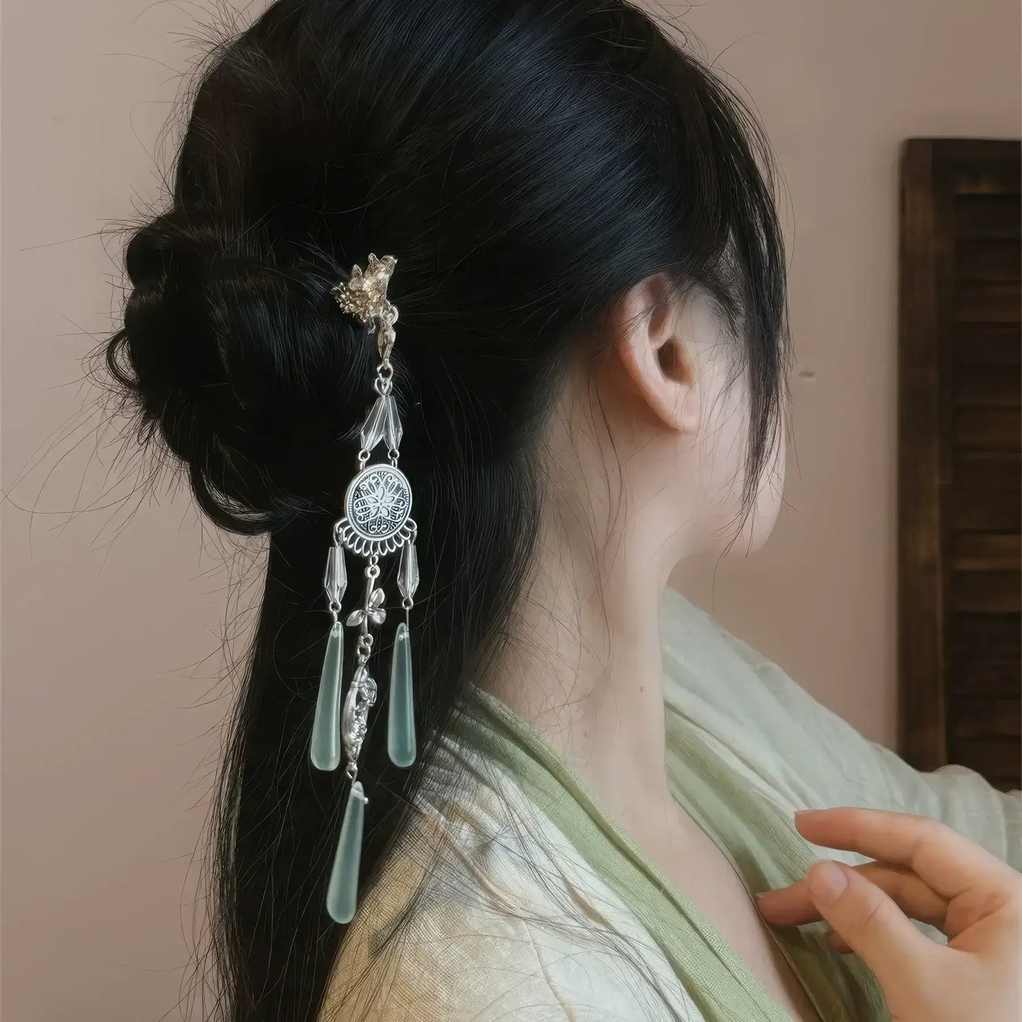 A close-up side view of the retro silver wind chime hairpin worn in a slightly messy bun, highlighting the layered tassels and delicate metalwork.