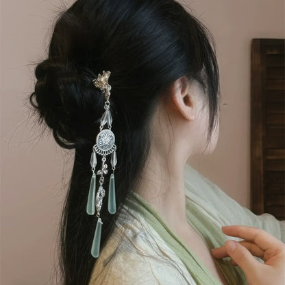 A close-up side view of the retro silver wind chime hairpin worn in a slightly messy bun, highlighting the layered tassels and delicate metalwork.