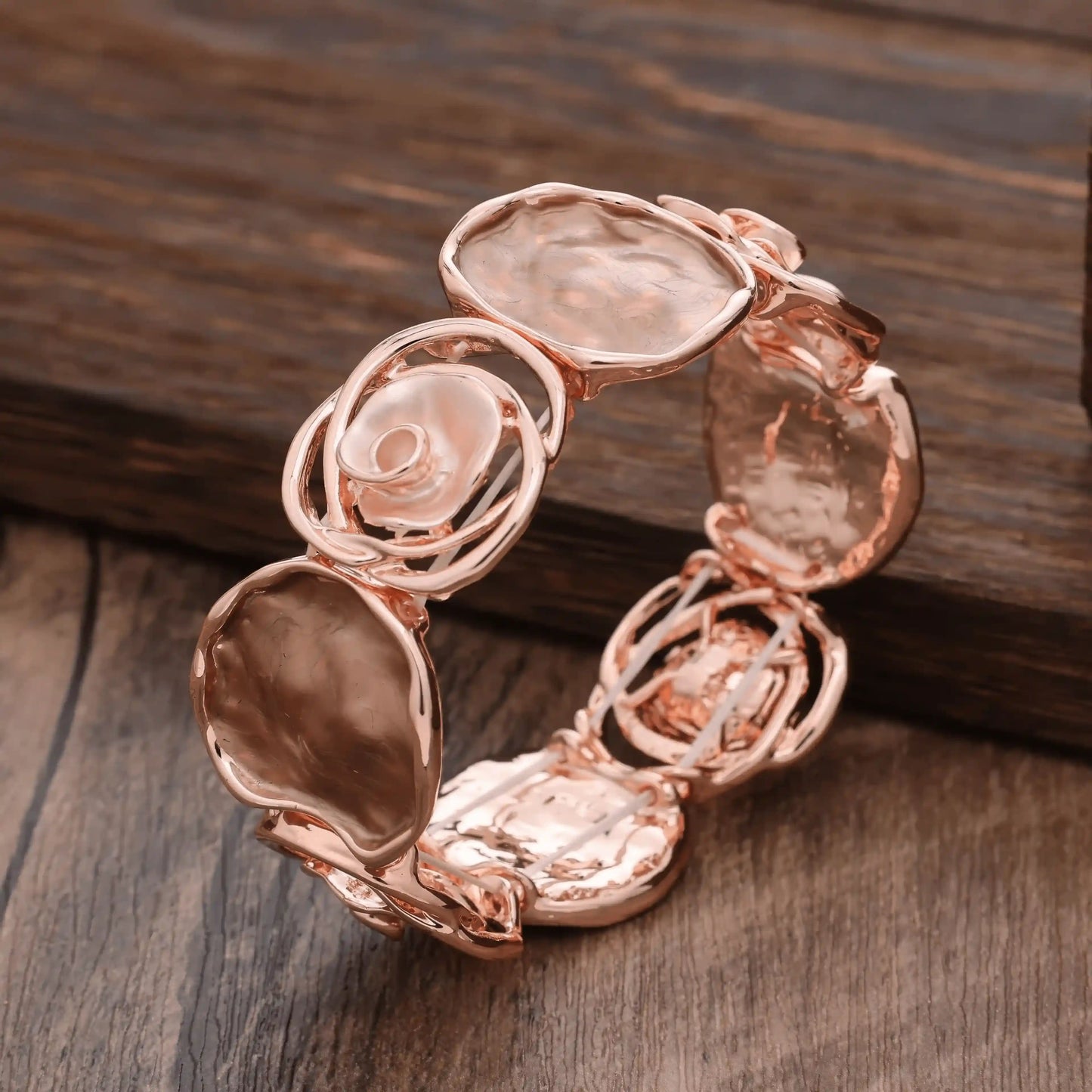 Rose - themed bracelet in rose gold with light - colored stones, placed on a wooden surface.
