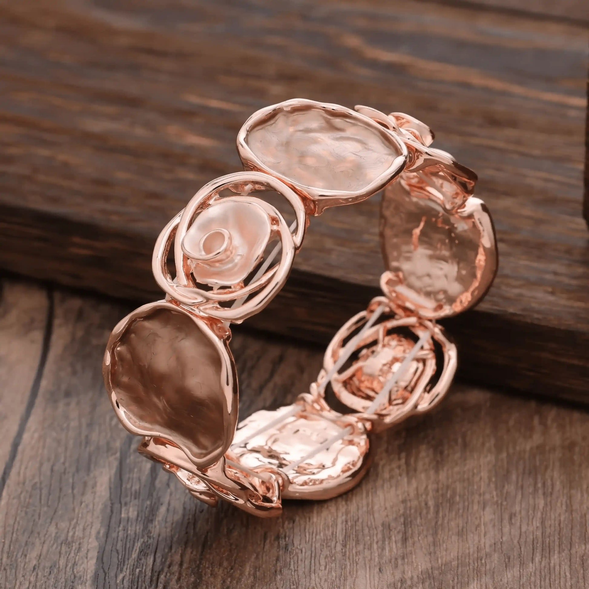 Rose - themed bracelet in rose gold with light - colored stones, placed on a wooden surface.