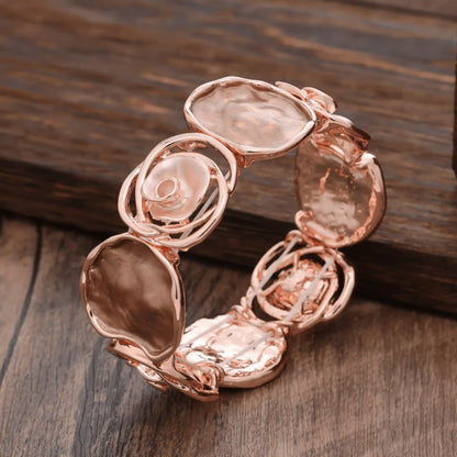 Rose - themed bracelet in rose gold with light - colored stones, placed on a wooden surface.