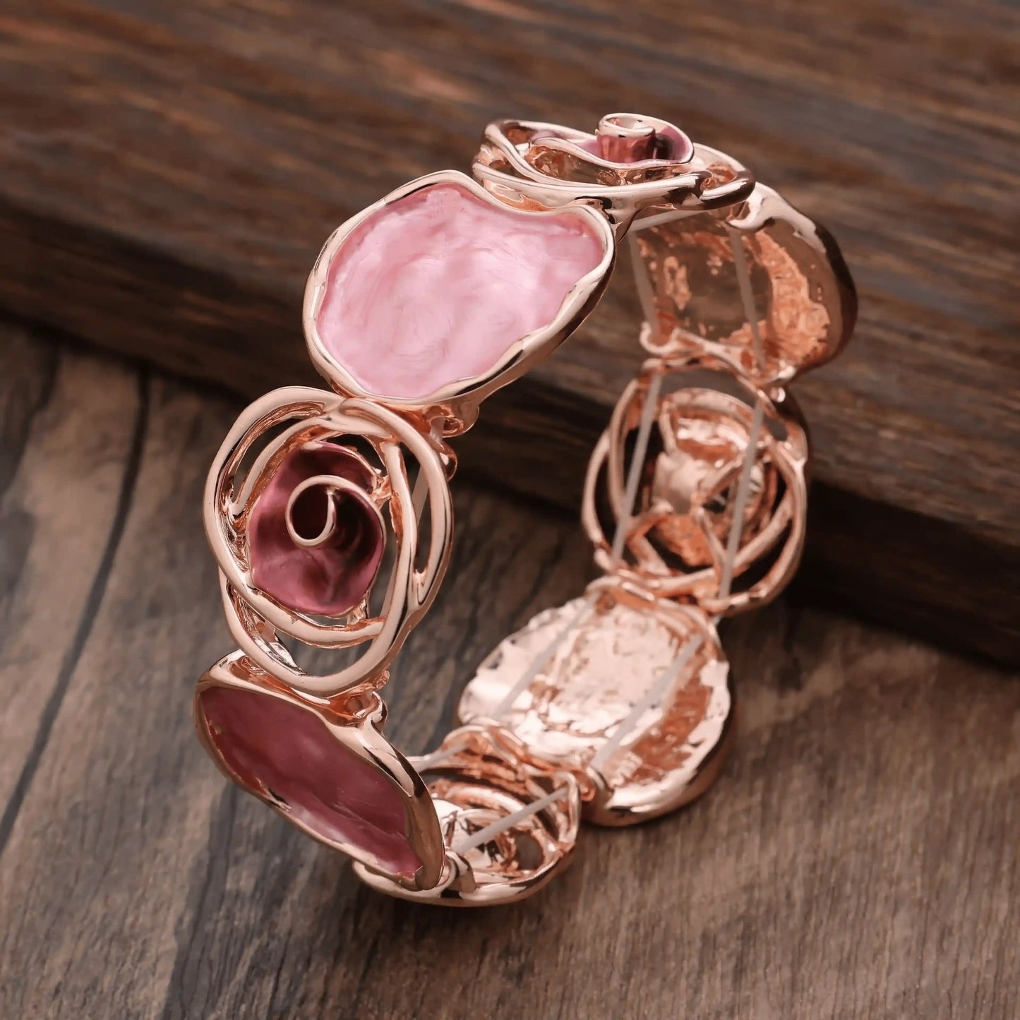 Rose - themed bracelet in rose gold with pink stones, placed on a wooden surface.