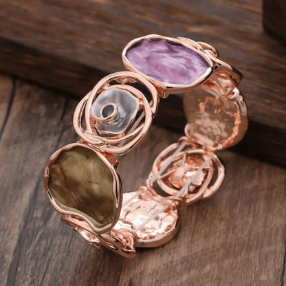  Rose - themed bracelet in rose gold with purple and brown stones, placed on a wooden surface.