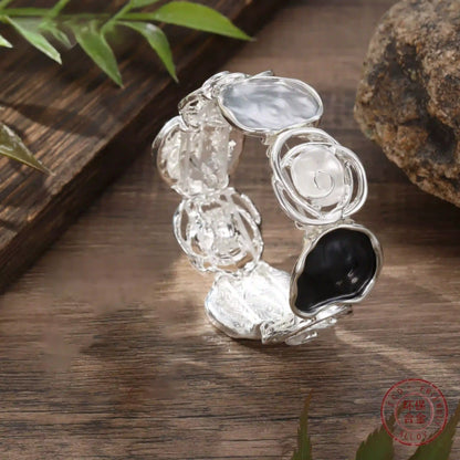 Rose - themed bracelet in silver with black and clear stones, placed on a wooden surface.
