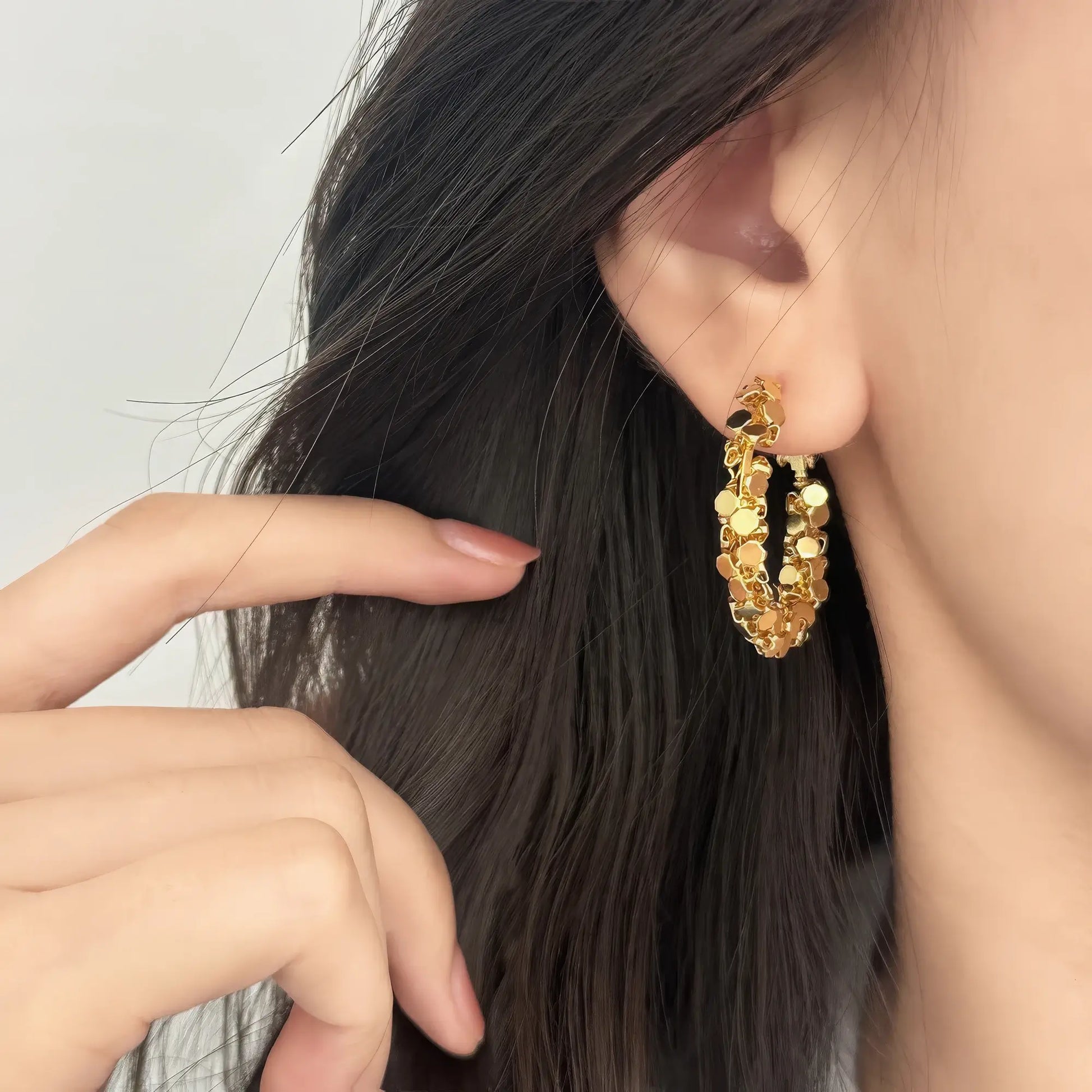 Gold sequined hoop earring worn, hand adjusting hair, showcasing the textured, sparkling design