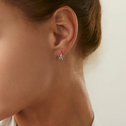 Silver bow tie stud earring worn on ear, showing a delicate and charming style.