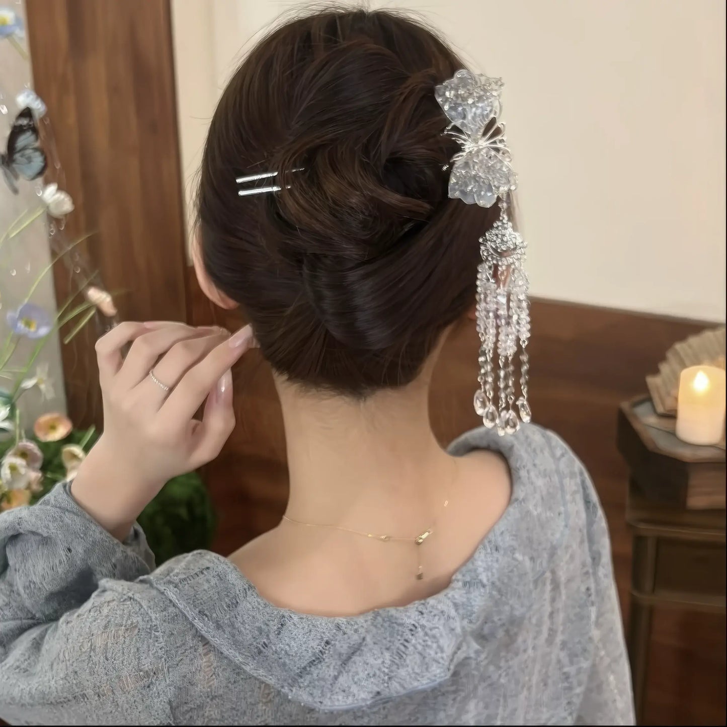 The hairpin in a polished updo, with the wearer adjusting it to show the full length and shimmer of the crystal tassels.