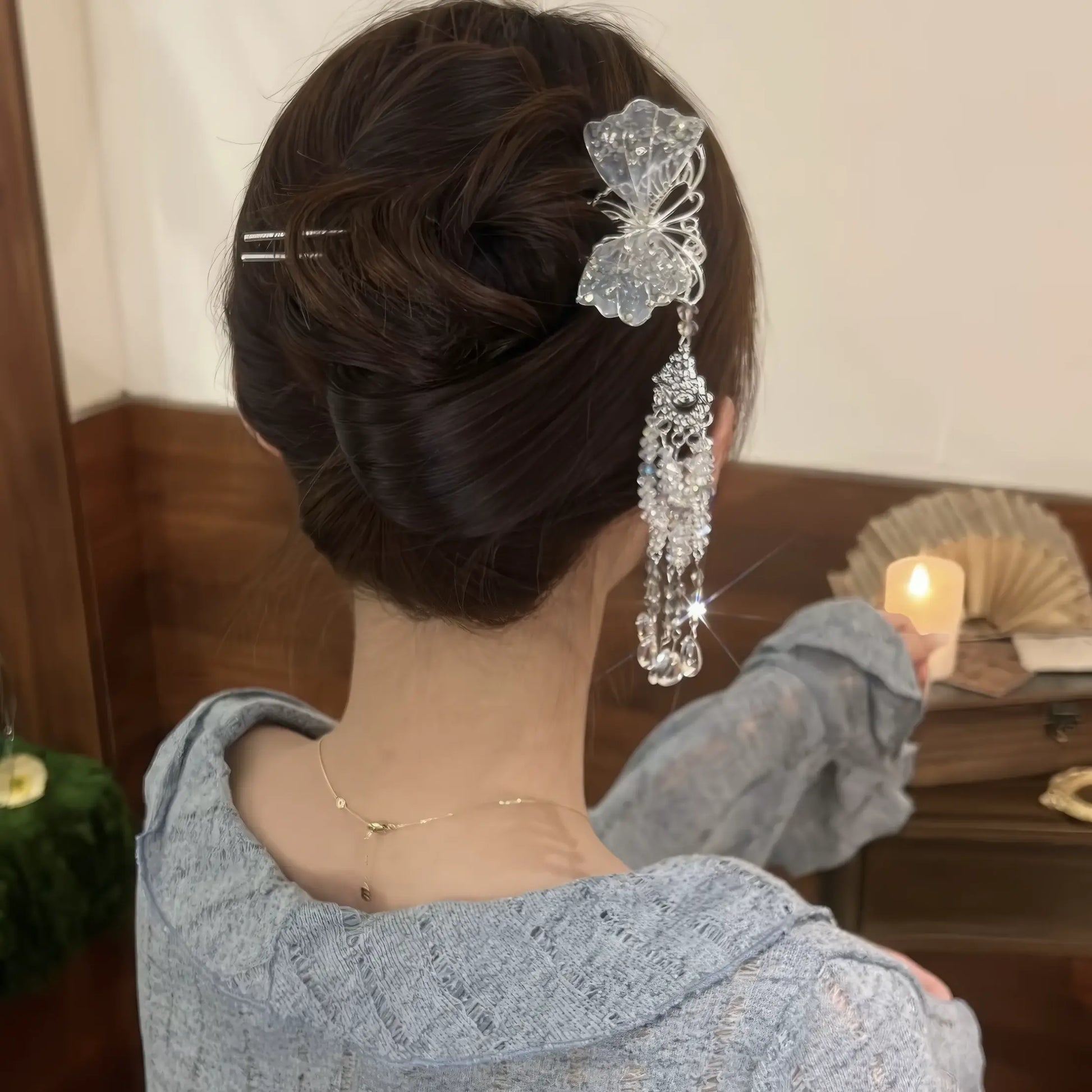  The silver butterfly hairpin worn in a neat low bun, with the long crystal tassel cascading down, highlighting its elegant drape.
