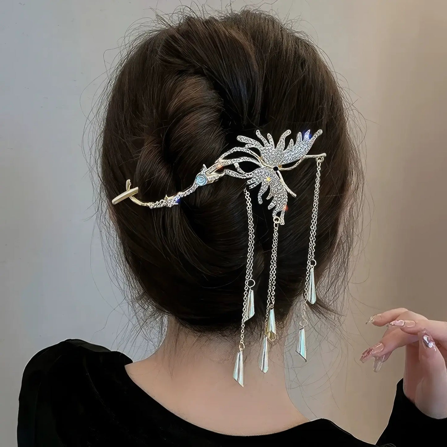 Silver butterfly hair clip styled in a textured messy bun, the sparkling crystals and dangling tassels catching light beautifully.