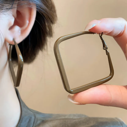 Pair of brown silver needle spray - painted square geometric earrings, hand - held and worn, showcasing the stylish, square look