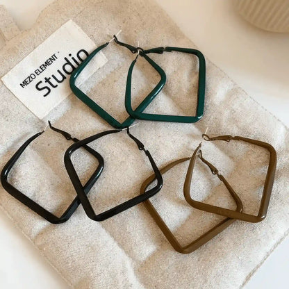  Mixed black, brown, and green silver needle spray - painted square geometric earrings, displayed on fabric, highlighting the variety of colors