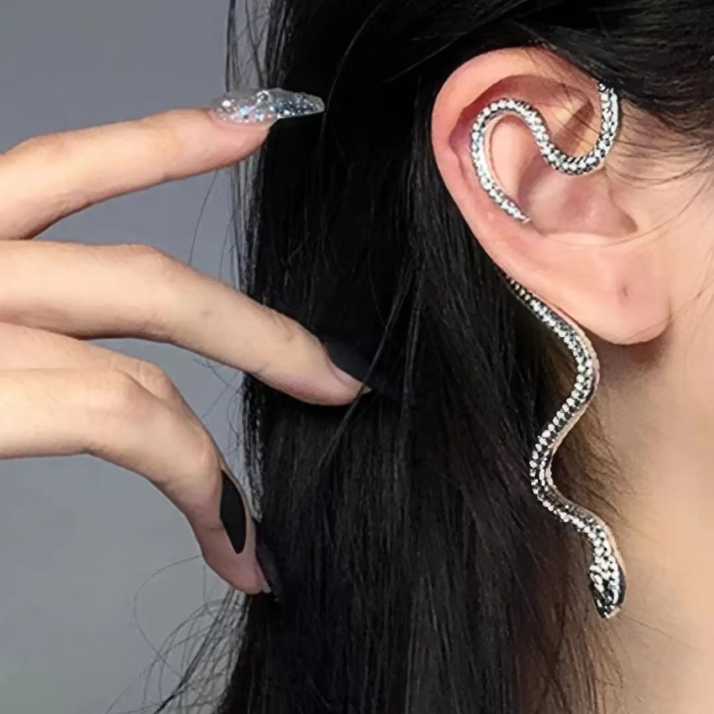 Silver snake - shaped wrapping ear cuff worn on ear, showcasing detailed snake design