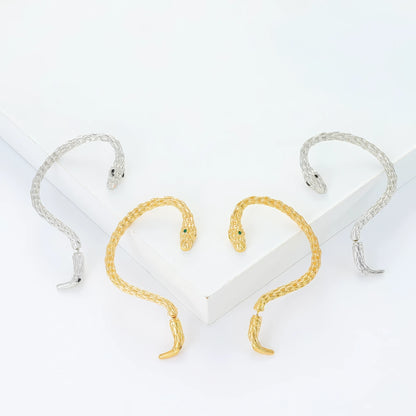 Mixed silver and gold snake - shaped ear cuffs, displayed on white surface, showcasing the variety of metallic tones.