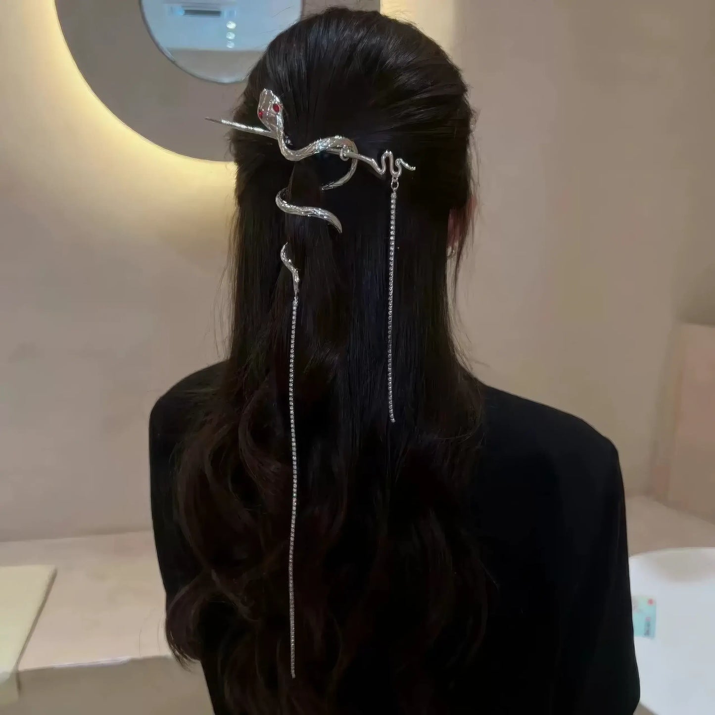 Loose wavy hair styled with a coiled snake hairpin, with multiple tassels falling vertically for a cool office-ready hairstyle.