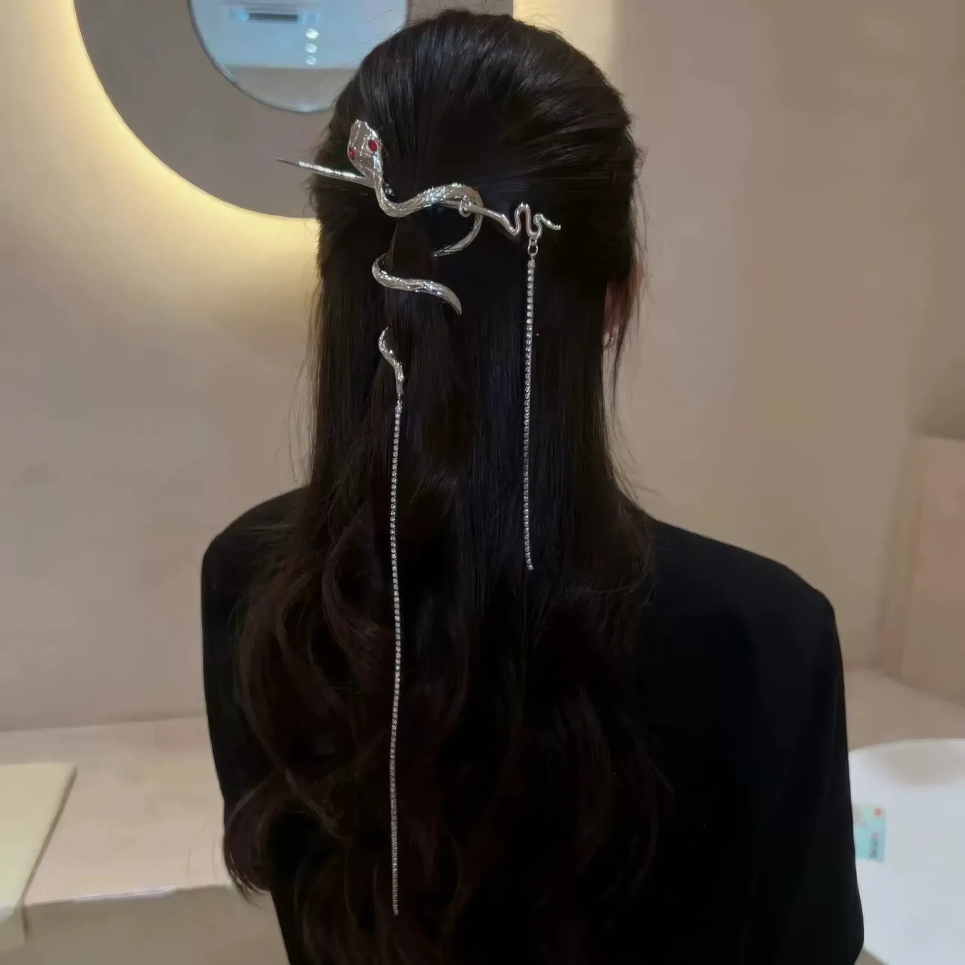 Loose wavy hair styled with a coiled snake hairpin, with multiple tassels falling vertically for a cool office-ready hairstyle.