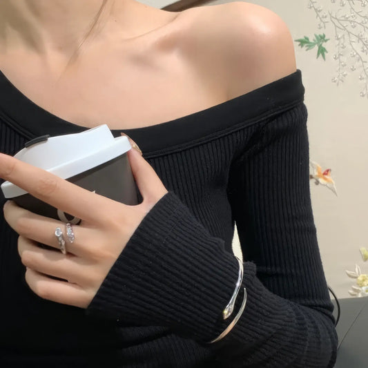 Sparkling diamond agile snake bracelet worn on wrist, with a dark - colored off - shoulder top.
