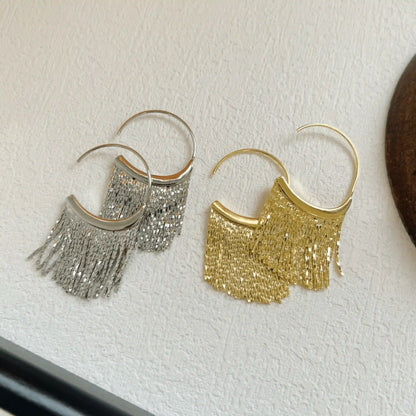 Mixed gold and silver tassel C - shaped earrings, isolated on white surface, showcasing the contrast of metallic tones