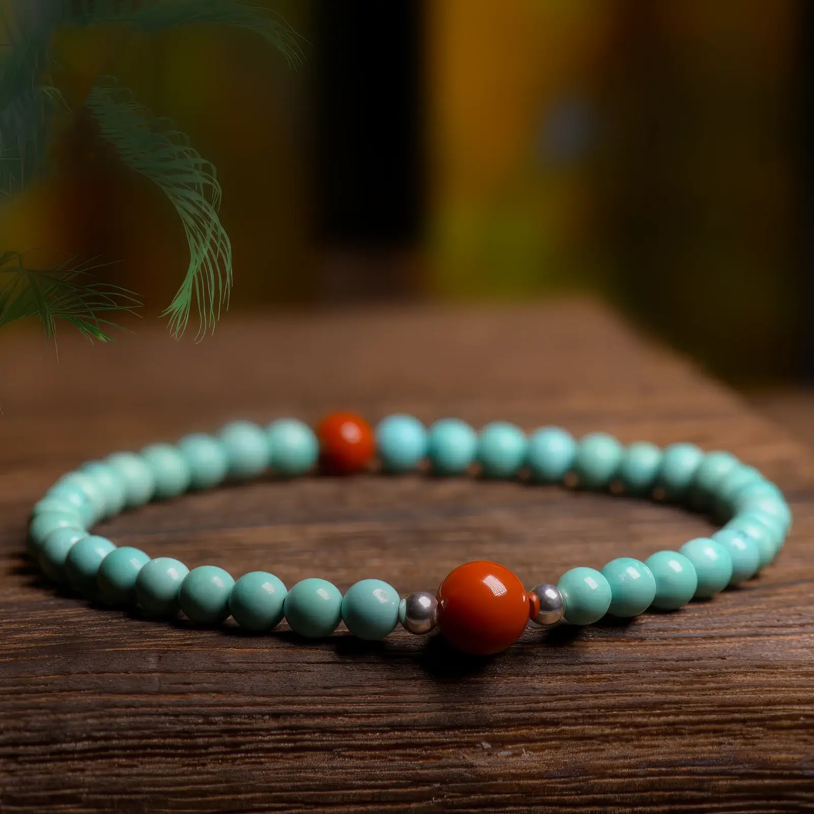 Turquoise bracelet with red beads placed on a wooden surface.
