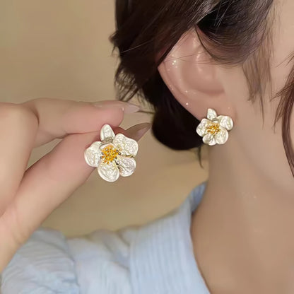 Two - tone new flower earring worn, hand adjusting it, highlighting the contrast of silver and gold on the ear