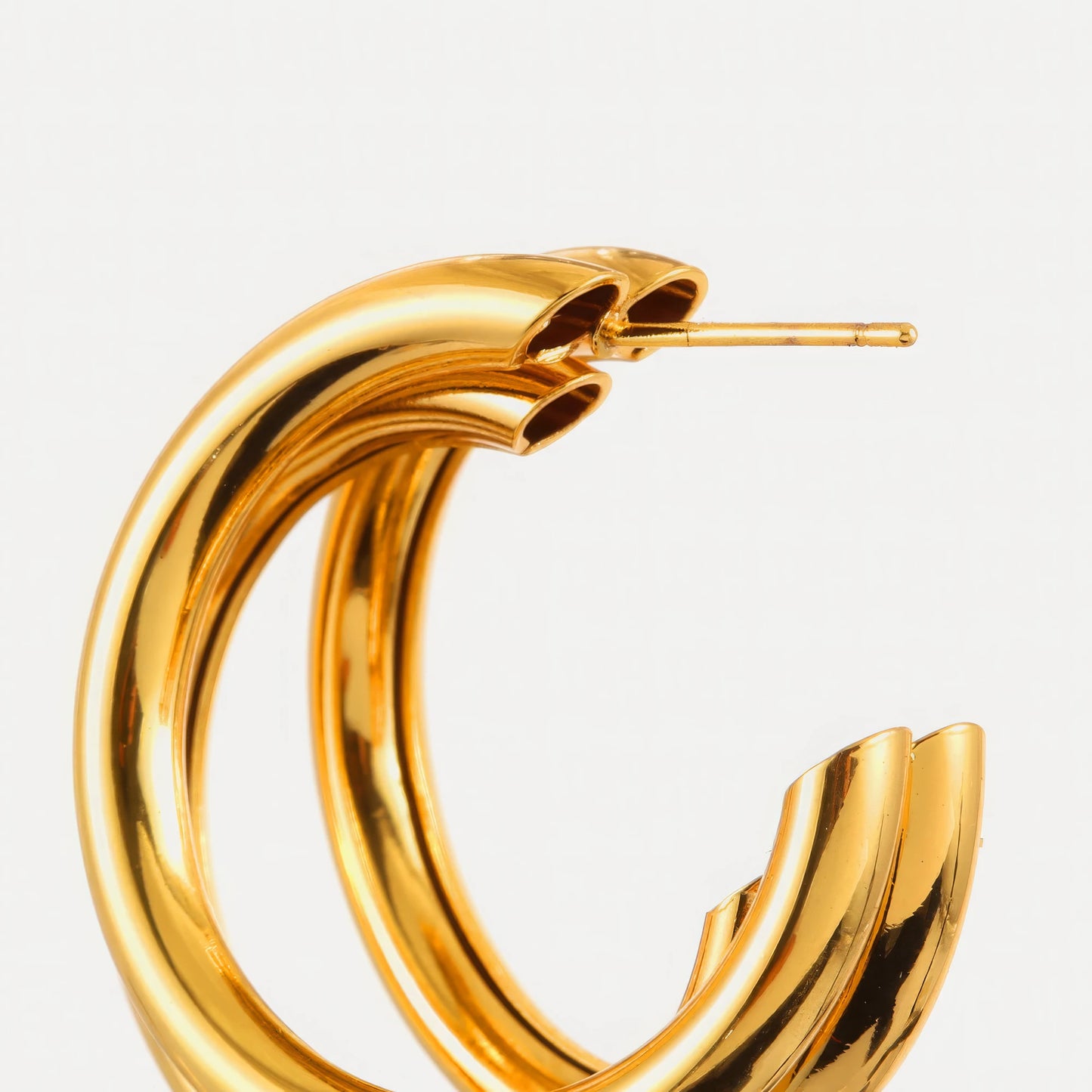 Close - up of gold unique - shaped hoop earring, showcasing the detailed, multi - layered structure