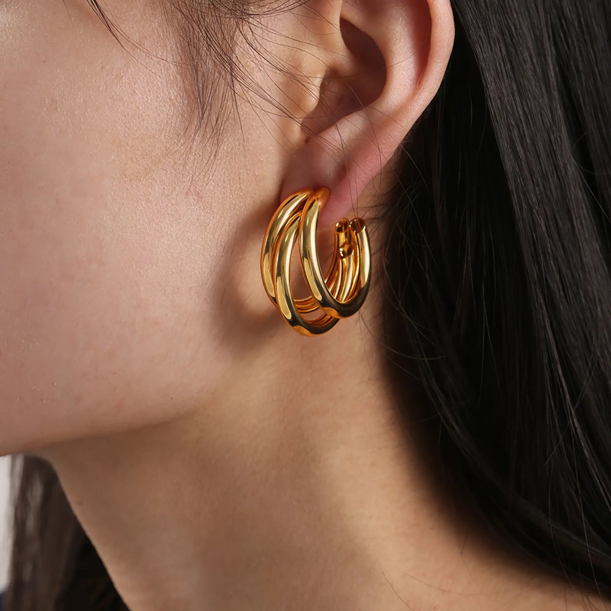Gold unique - shaped hoop earring worn, highlighting the bold, multi - layered look on the ear
