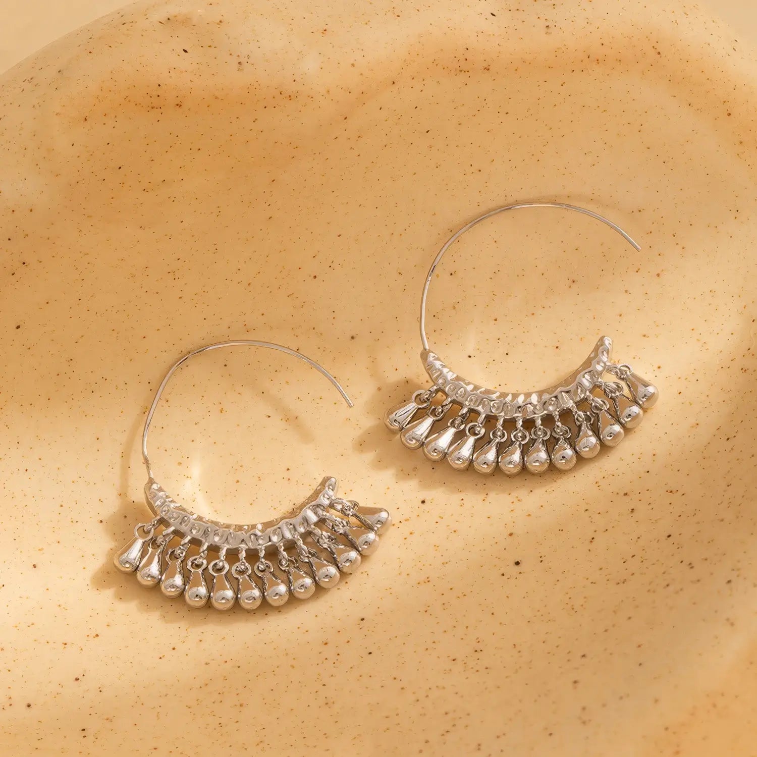  Silver water drop tassel earrings, displayed on a textured surface, emphasizing the detailed, dangling water drop design